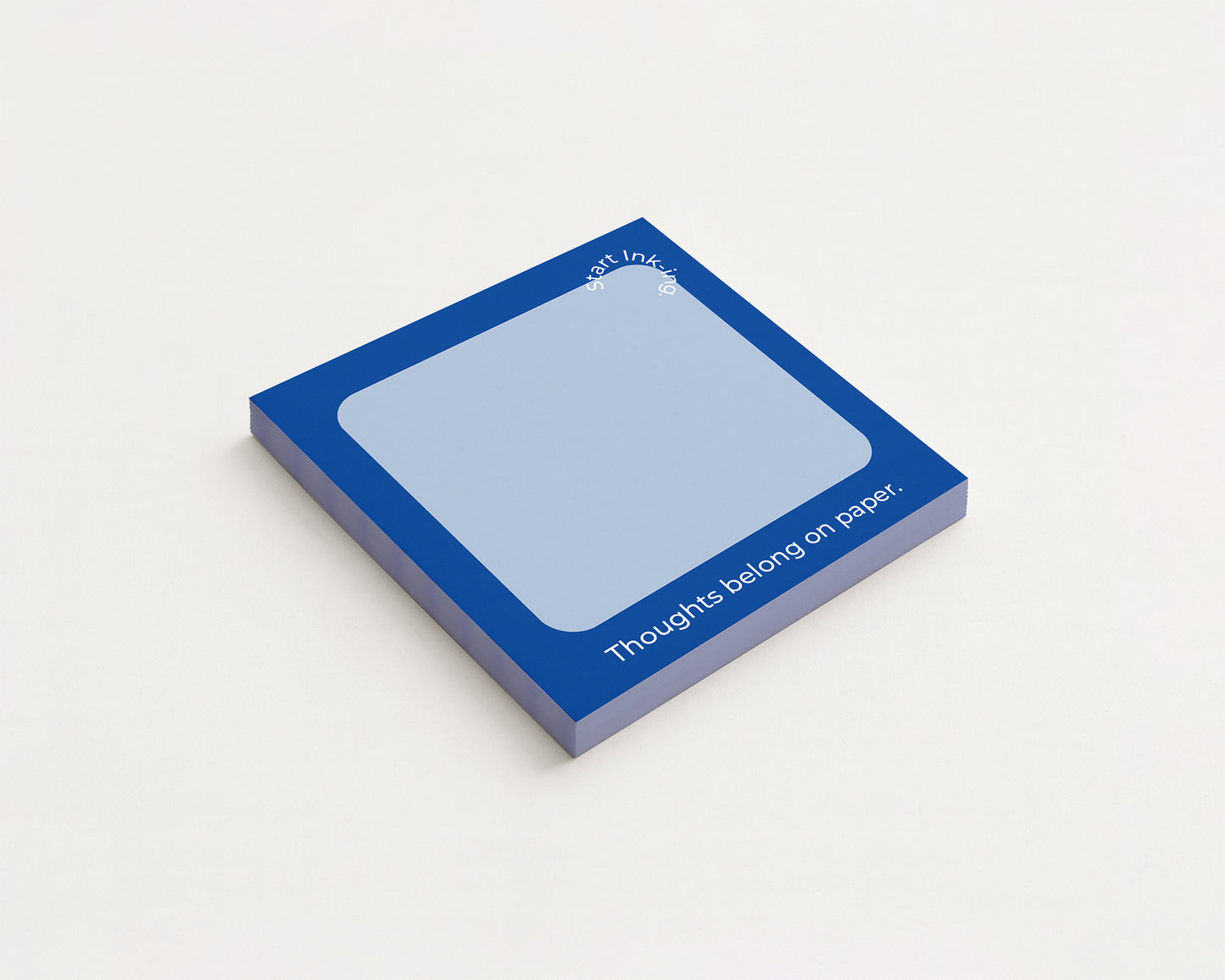 A single square sticky note pad with a dark blue border and a pale blue writing area, shown at an angle on a clean off-white background. White text on the pad reads 'all ideas belong on paper.